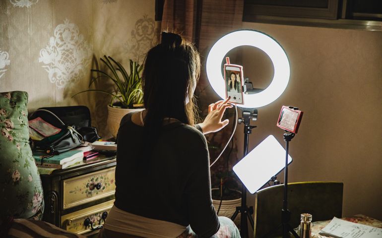 asian female influencer filming content using phone in a bedroom