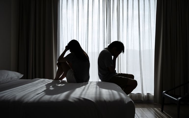 Depressed couple having a problem sitting head in hands in the dark bedroom, Negative emotion and mental health concept