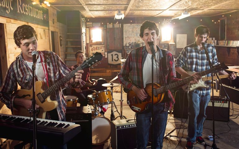 Teenage friends singing and playing guitar during band practice in garage