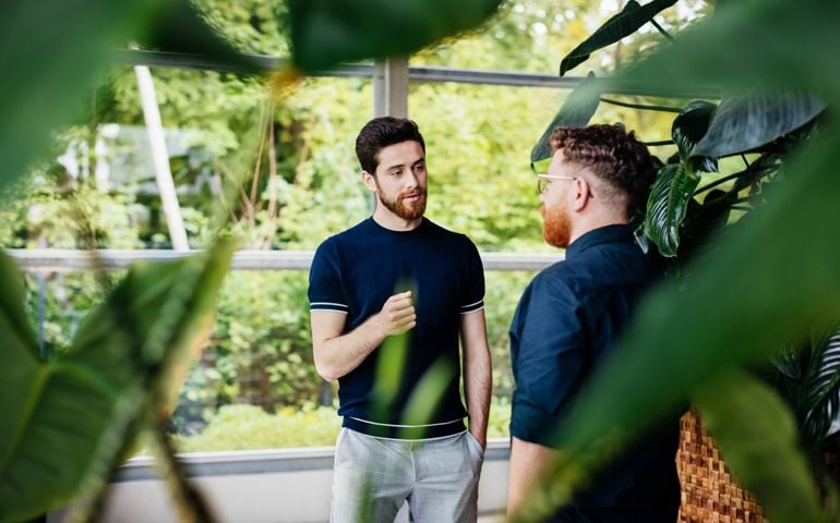 Two Colleagues Talking Amongst Plants In Green Office