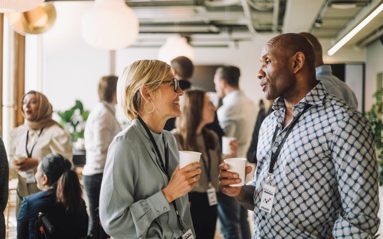 Mature businesswoman talking with male colleagues in break at convention center
