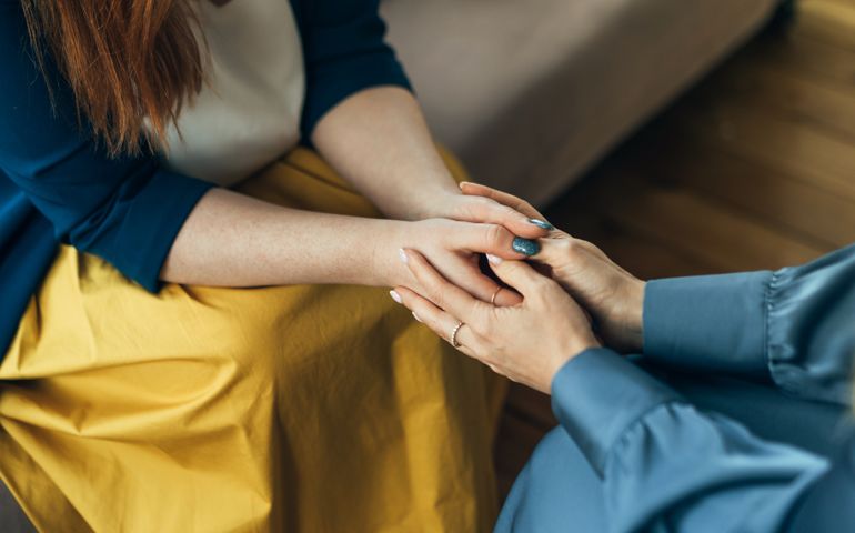 Two women sitting in armchairs and talking. Woman psychologist talking to patient