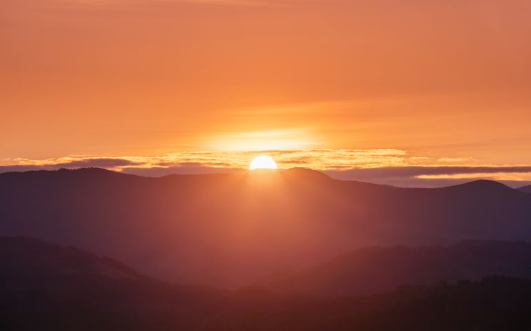 Beautiful sunrise. Sun rays enlighten the meadow with trees. Spring morning. Landscape with high mountains. Panoramic view. Natural scenery. Wallpaper background. Touristic place Carpathian park.