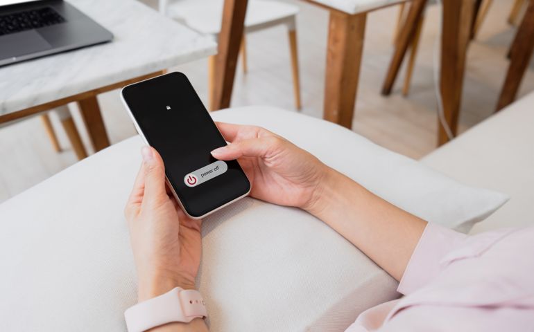 Woman hand using is sliding to turn off the mobile phone to reduce power consumption. Technology and environment concept