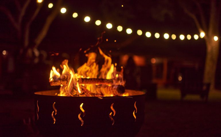 Bonfire burning in a garden a summer night, unknown people in the background.dark