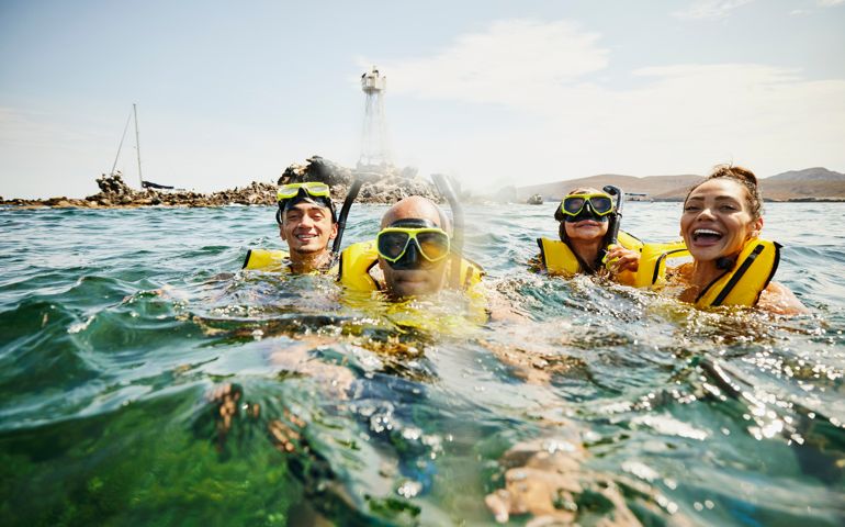 Medium shot of smiling family on snorkeling tour in tropical ocean