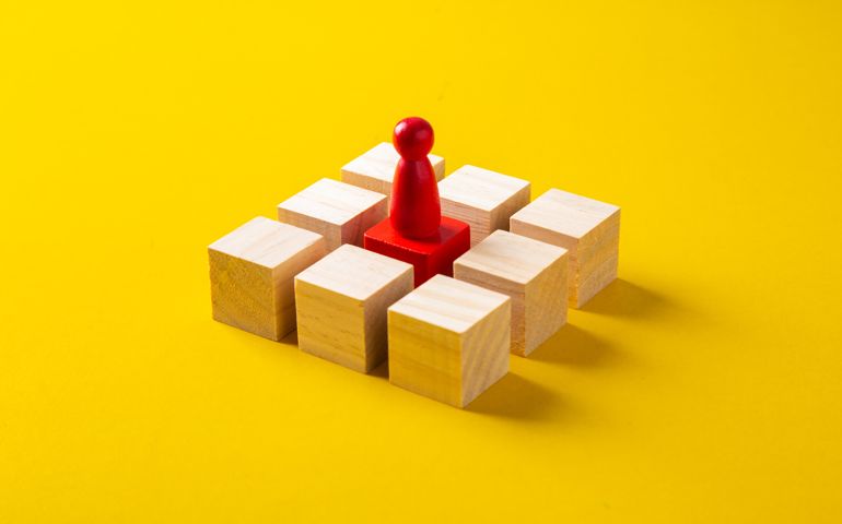 Red wooden block standing out from the group wooden blocks on yellow background,Malaysia