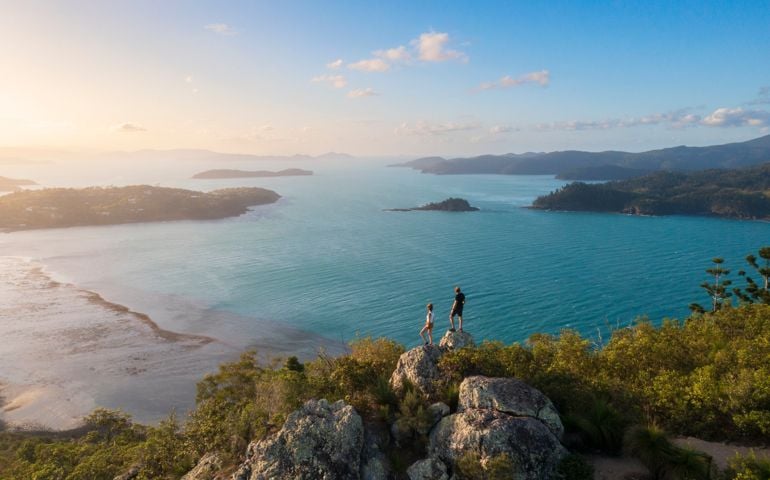 Couple enjoying the view on top mountain overlooking Whitsundays ocean