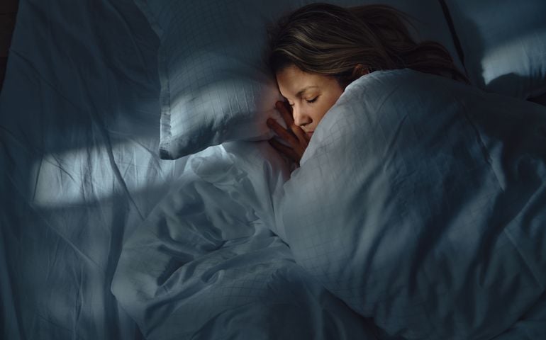 Above view of relaxed woman sleeping in bed at night.