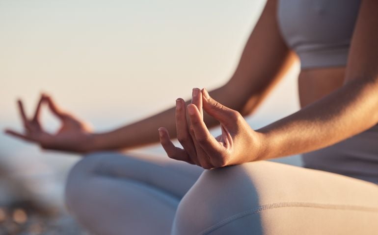 Woman, hands or lotus pose meditation on sunset beach, ocean or sea in mental health, mind training or chakra balance. Zoom, peace or zen yogi in calm mudra, relax yoga wellness or sunrise gratitude