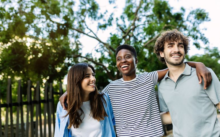 United multiracial friends having fun embracing and walking together outdoor
