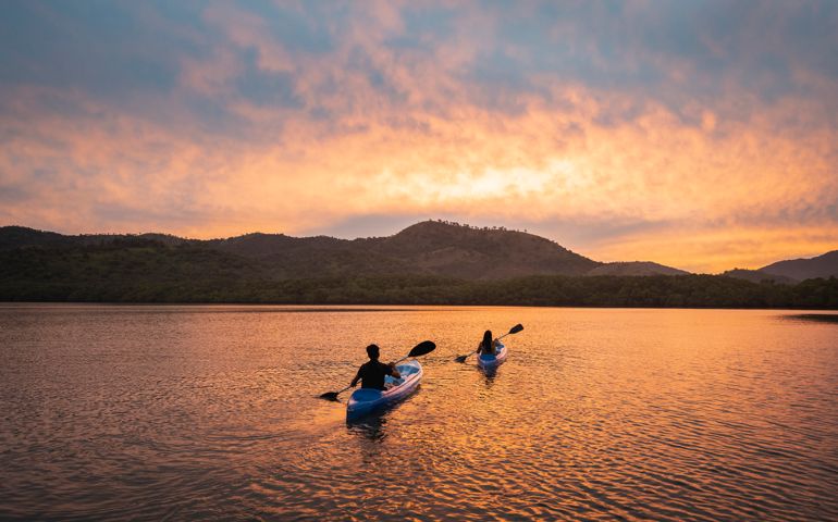 Two people kayaking in a lagoon at sunset