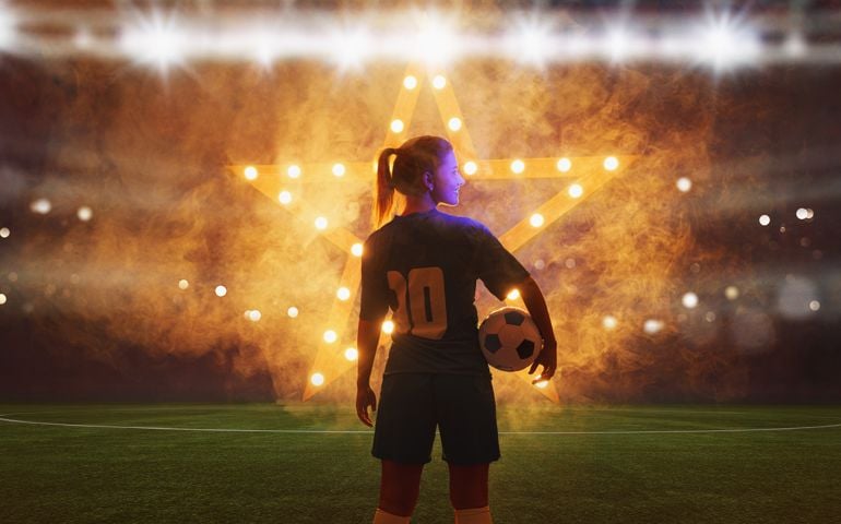 Portrait of young female soccer player with soccer ball standing with a shining star in the back