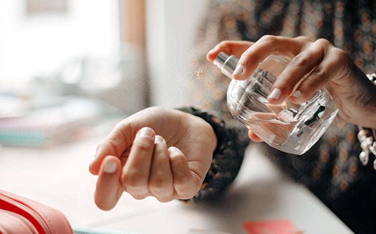 Woman spraying perfume on wrist
