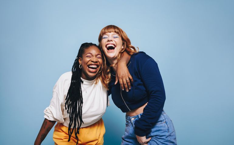 Two interracial best friends laughing and having a good time together in a studio