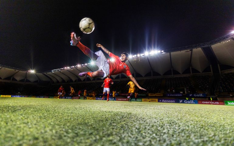 Wide shot photo of male athlete impressively bicycle kicking a soccer ball while in mid-air