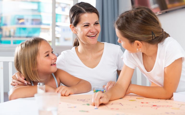 Woman and two daughters playing board games