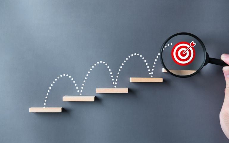 Unlock potential of business success stairs dart and dartboard targets magnifying glass with hand on gray background. Explore opportunities growth embrace steps to achieve ambitions and goal concept.