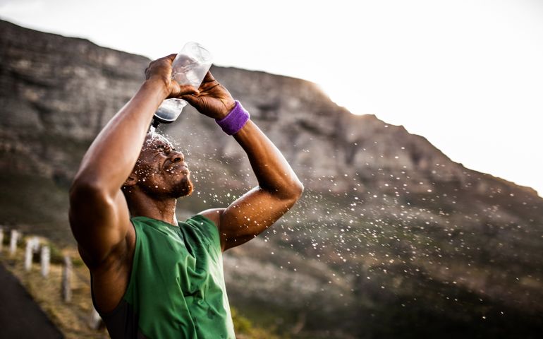 Athlete splashing himself with water from his water bottle