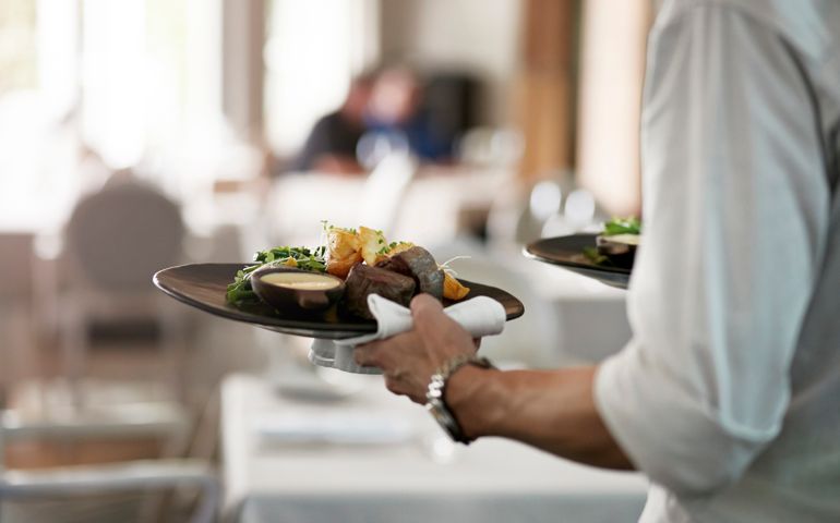 Close-up of waiter walkiing with dishes