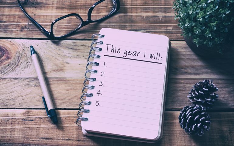 New Year Resolutions List on Notepad on Top of Wood Desk