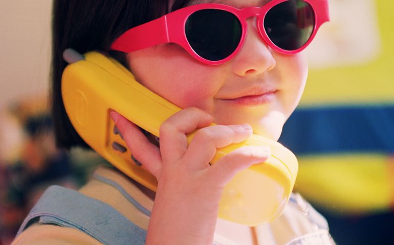 Girl (3-5) wearing red sunglasses, holding toy phone (Enhancement)