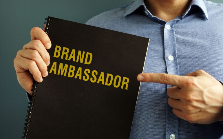 Man is holding book with title Brand Ambassador.