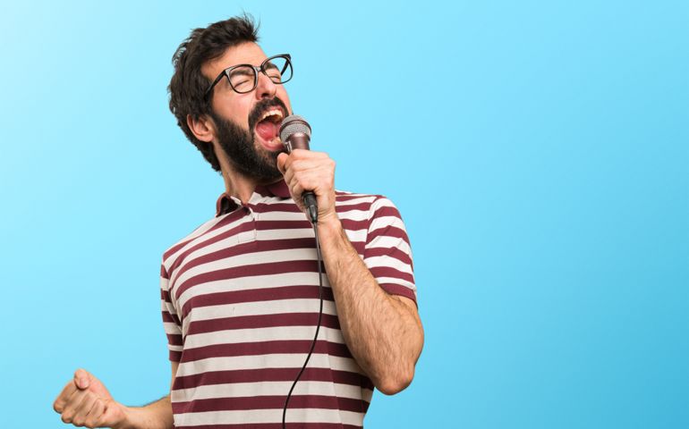 Man with glasses singing with microphone on colorful background