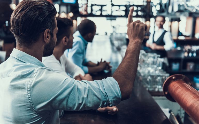 Young Man Ordering One Beer in Modern Bar. Sitting in Pub. Bottle of Beer. Young Men with Beer. Men Meeting in Modern Pub. Friendship Concept. Communication with Friends Concept.