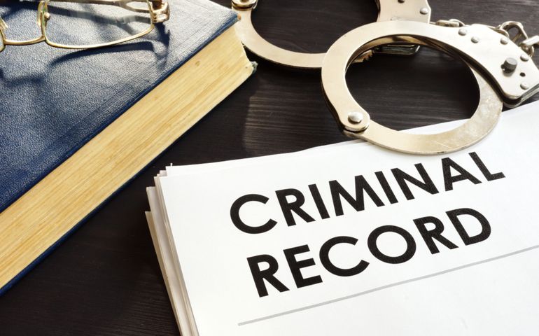 Criminal record and handcuffs on a desk.