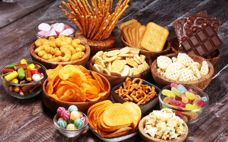 Salty snacks. Pretzels, chips, crackers in wooden bowls. Unhealthy products. food bad for figure, skin, heart and teeth. Assortment of fast carbohydrates food.