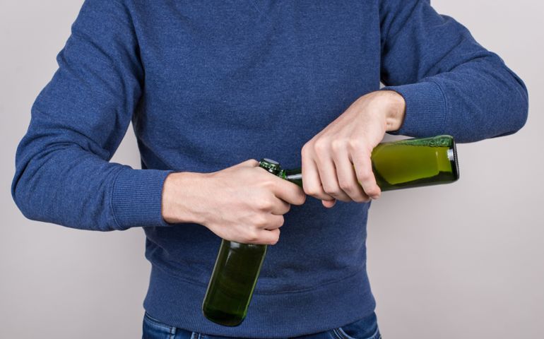 Cropped close-up photo of skilled party goer showing his talant in opening bottles isolated grey background