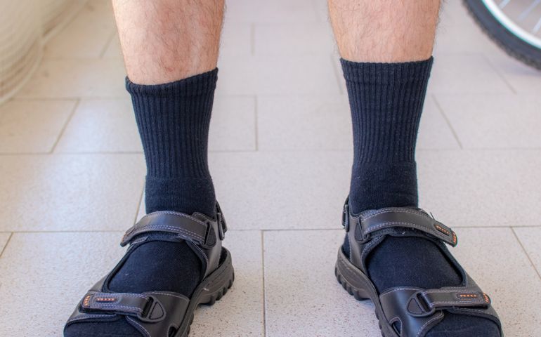 Close up shot of a man wearing black socks with sandals.