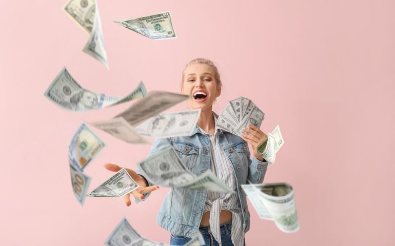 Beautiful young woman with flying money on color background