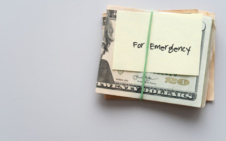 Dollars cash money and paper note with text written FOR EMERGENCY on copy space background - concept of financial planning saving money goal on purpose of rainy day crisis tough time