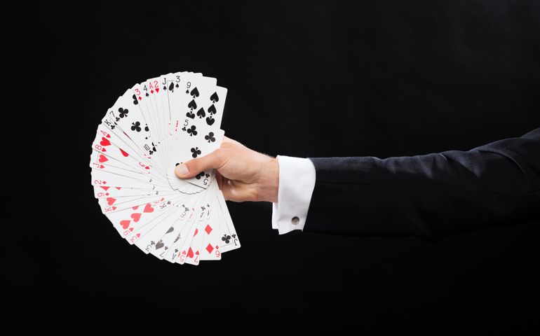 magic, performance, circus, gambling, casino, poker, show concept - close up of magician hand holding playing cards