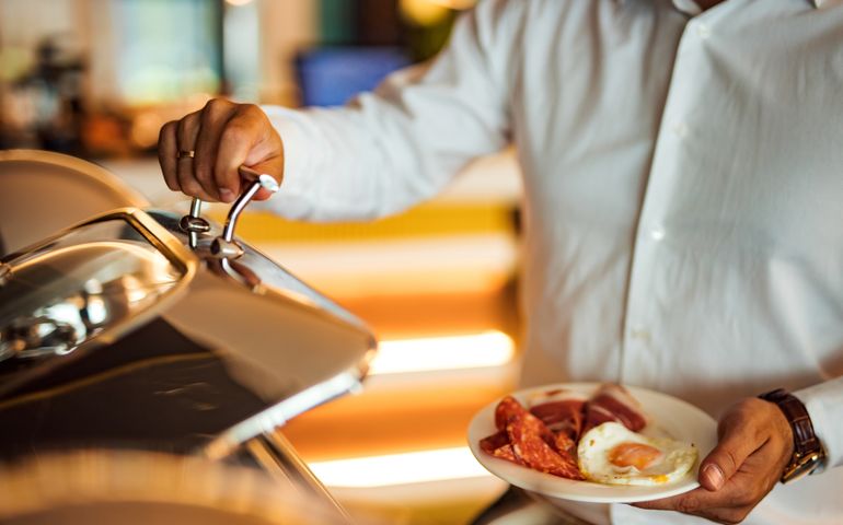 Man with food at breakfast buffet, close-up.