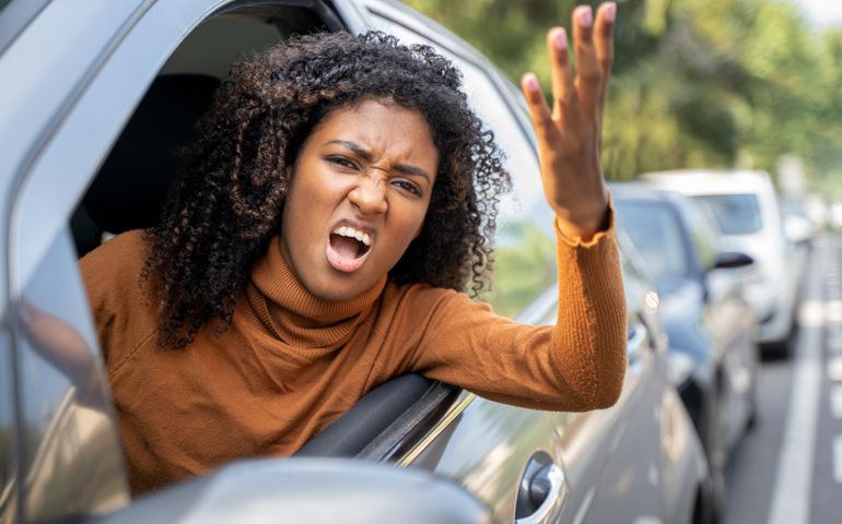 Aggressive woman driving car shouting at someone