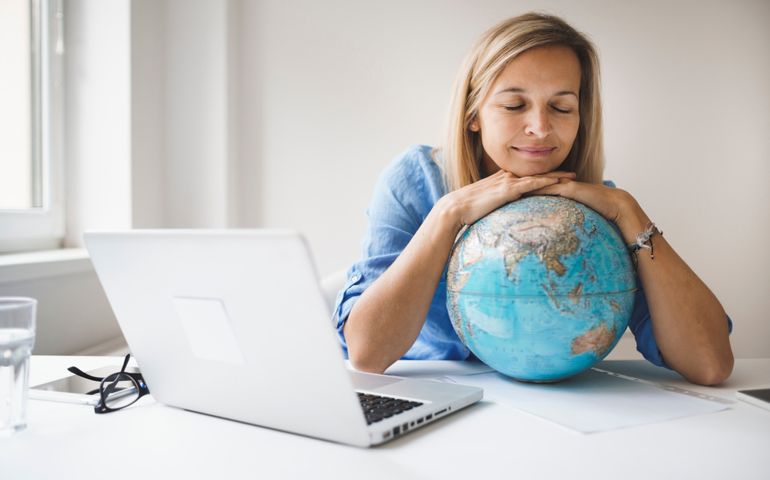 blond woman is relaxing on globe and dreaming of travelling during corona covid-19 time
