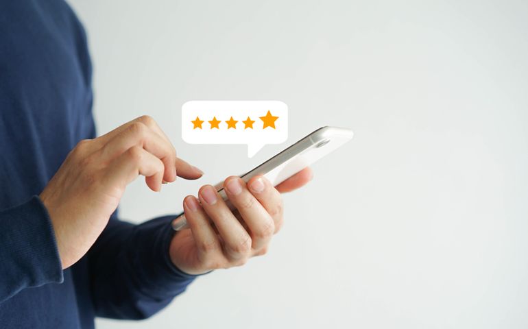 close up on customer man hand pressing on smartphone screen with gold five star rating feedback icon and press level excellent rank for giving best score point to review the service , business concept