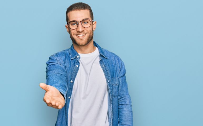 Young caucasian man wearing casual clothes smiling cheerful offering palm hand giving assistance and acceptance.