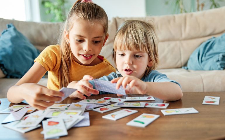 Portrait of brother and sister having fun together playing board game at home