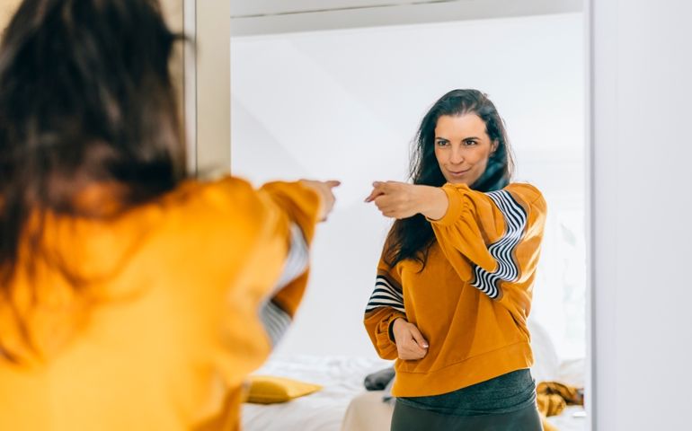 Self confident single woman pointing finger at her reflection in mirror, dancing and felling good. Independent person with high self esteem talks positive and I can do it motivation.