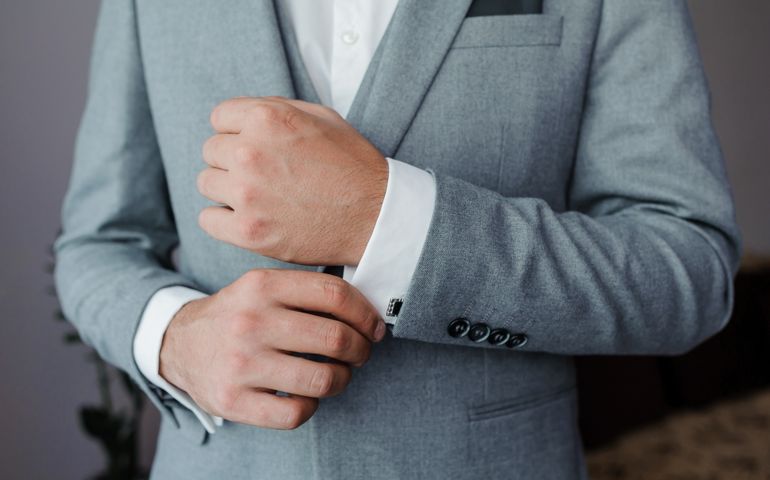 A groom fastening a cuff-link on the shirt. Men fastening a cufflink on their shirt