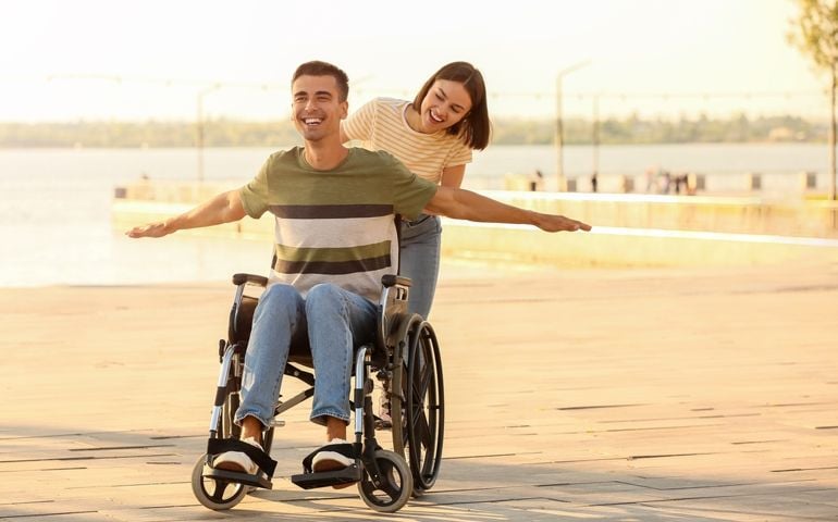 Young man with physical disability and his wife outdoors