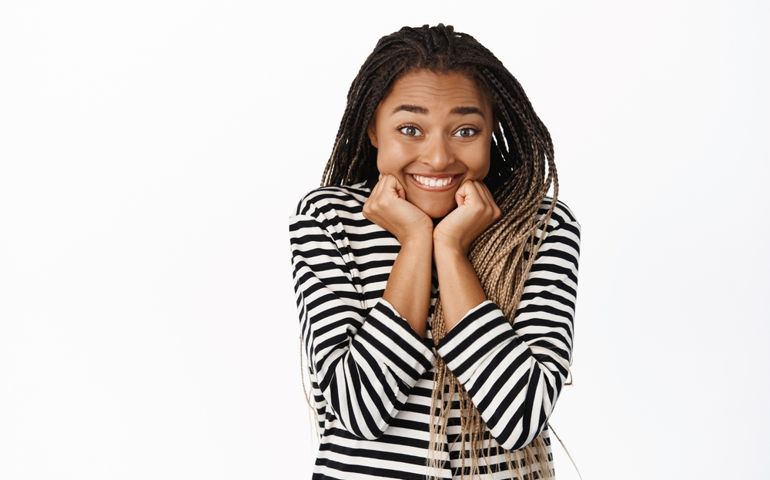 Smiling excited black girl waiting for smth with anticipation, yearning, looking with interest and amusement at camera, standing over white background