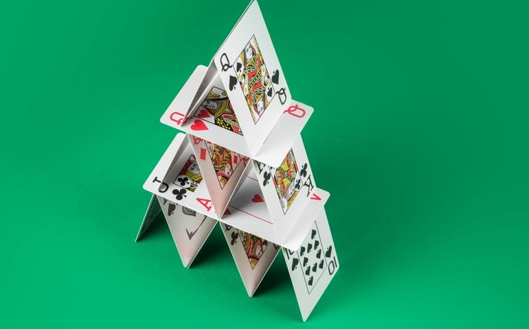 Card house made on green casino table.
