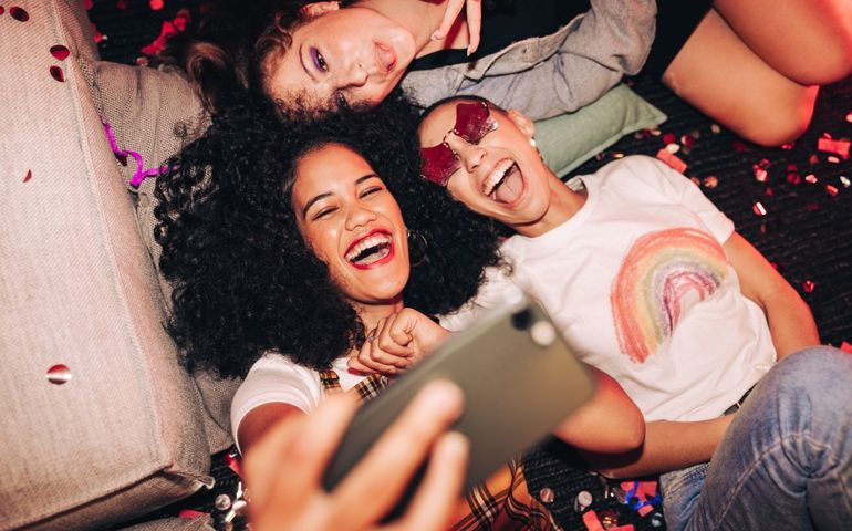 Vibrant selfies for vibrant people. Overhead view of three happy friends taking a selfie while lying on the floor at a house party. Group of cheerful female friends having fun together on the weekend.