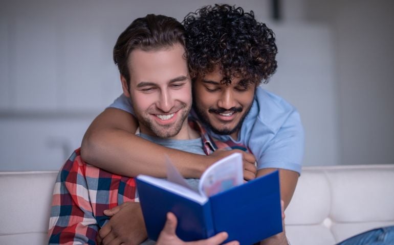 Man with a textbook embraced by his romantic boyfriend
