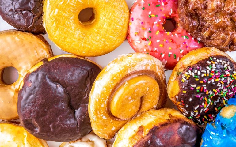 Dozen assorted donuts with Chocolate, Boston Creme, Cinnamon Bun, glazed and maple, close up photograph.